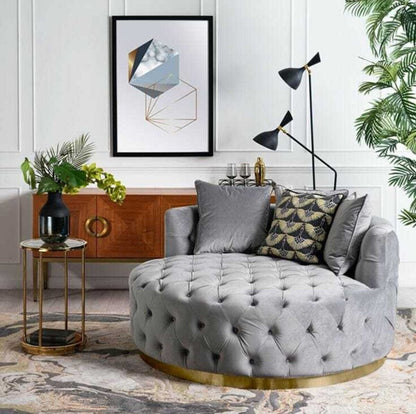 Okrągła pikowana sofa w szarym kolorze, w eleganckim wnętrzu.