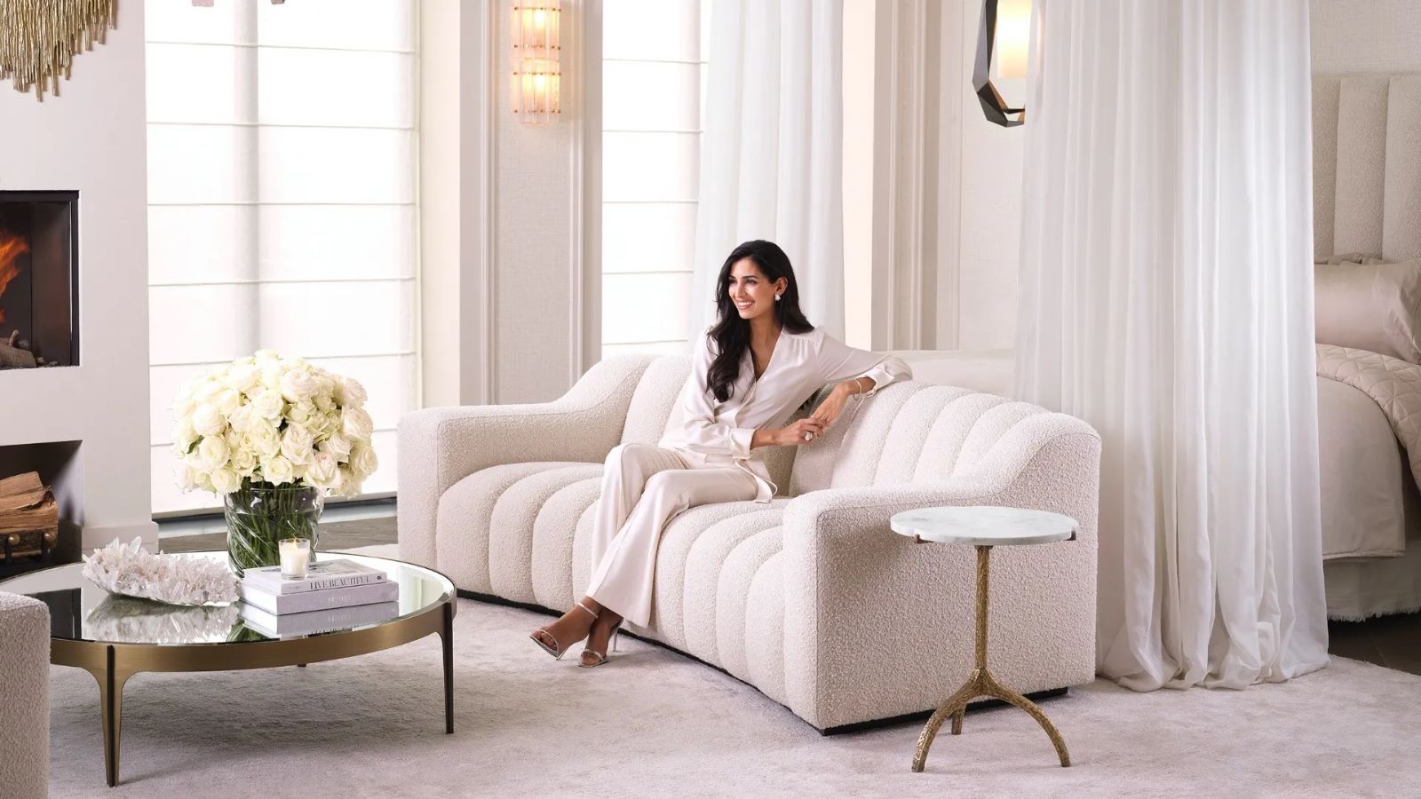 Beżowa, tapicerowana sofa o nowoczesnym, falistym kształcie z pionowymi przeszyciami.