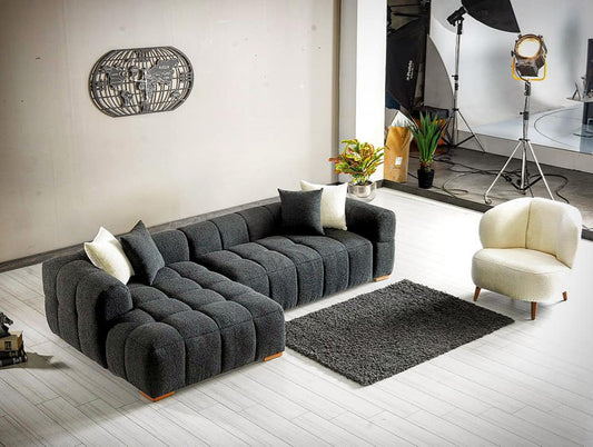 Ciemnoszara narożna sofa w nowoczesnym salonie z dużymi oknami.